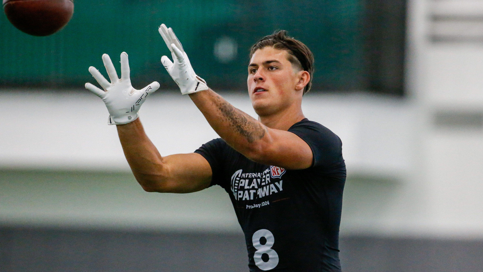 Former Wales wing Louis Rees-Zammit catching an American football.