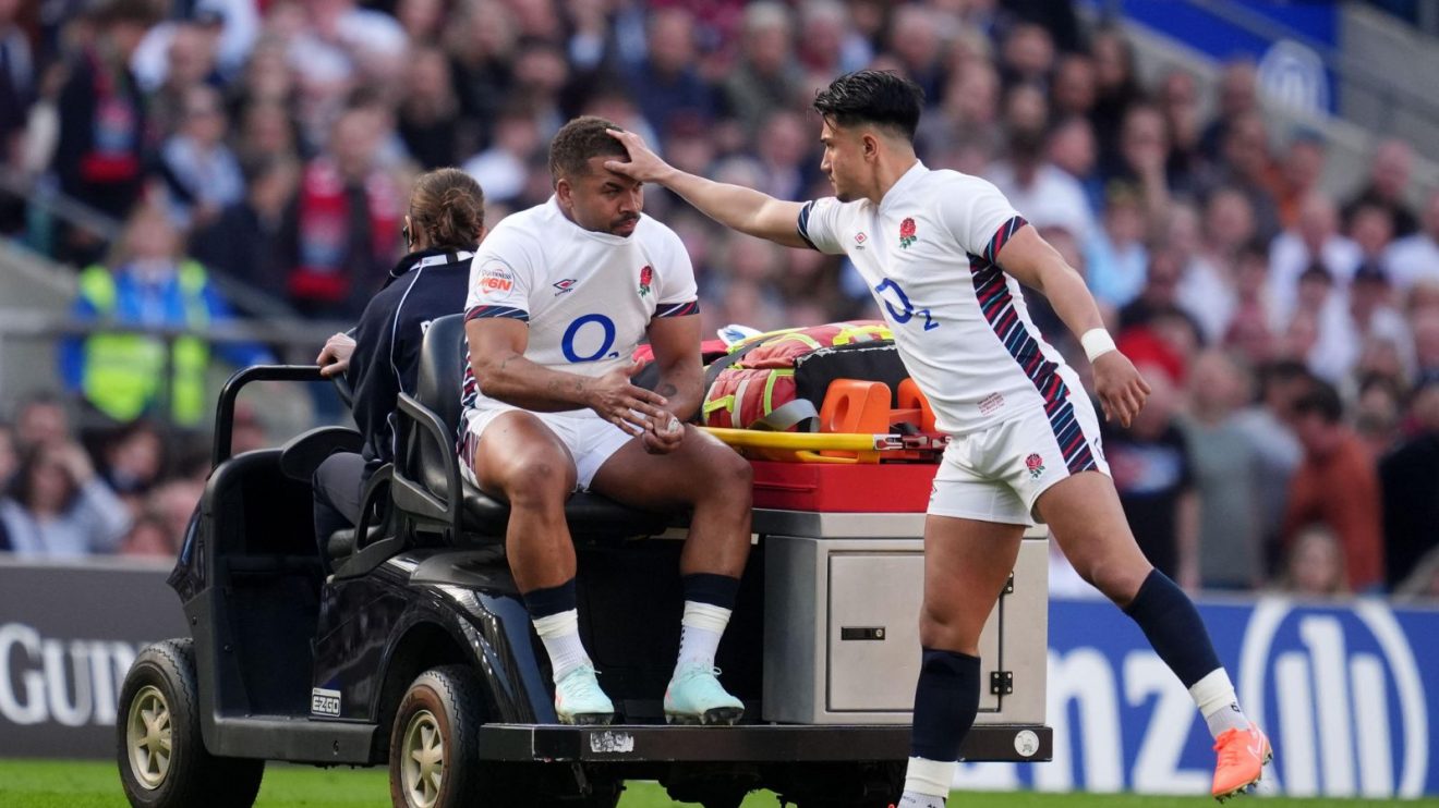 England centre Ollie Lawrence being stretchered off the pitch and consoled by Marcus Smith